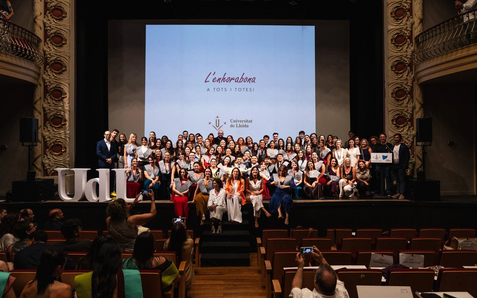 Toda la promoción de Enfermería posa en el escenario del teatro el día de la graduación