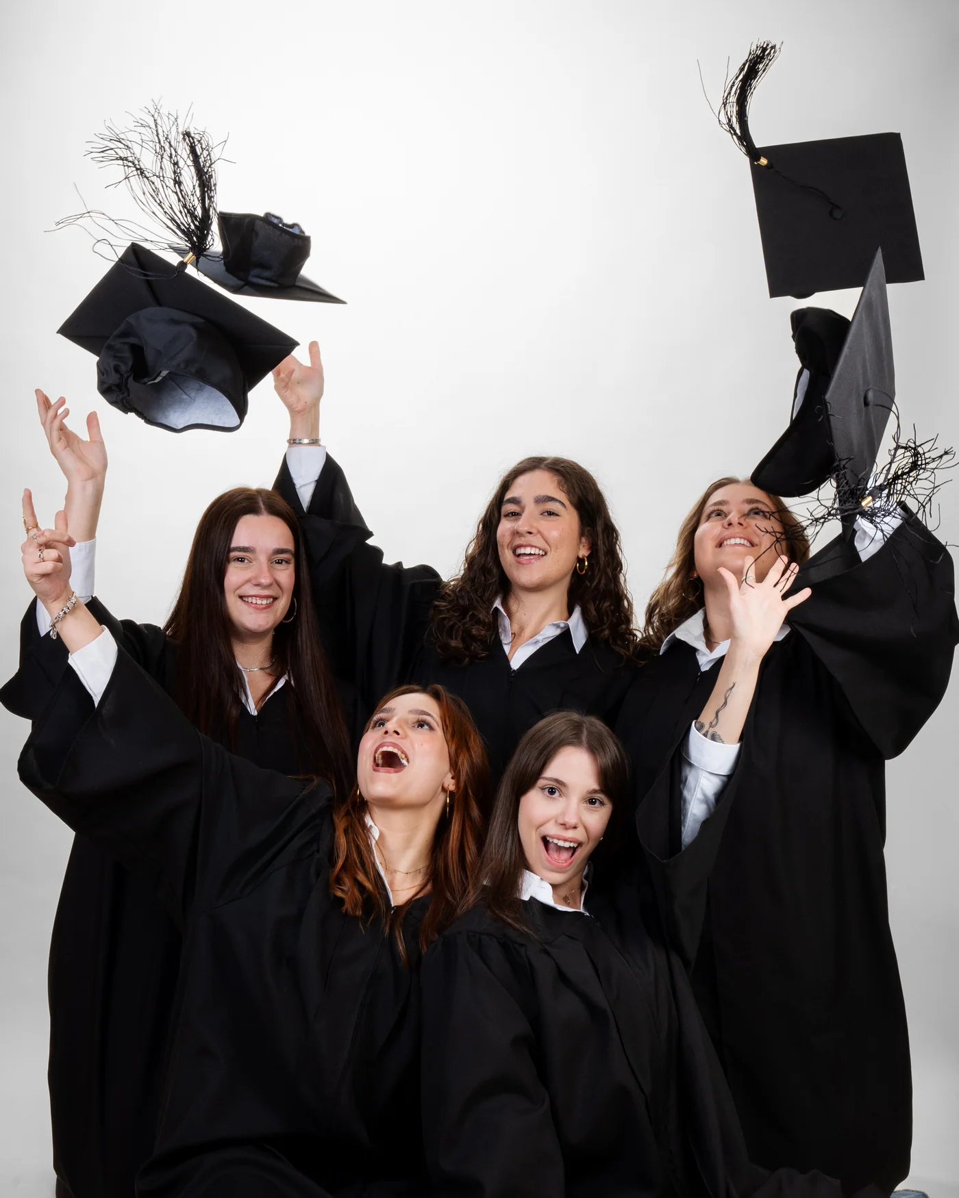 Cinco graduadas con toga lanzan el birrete al aire en el estudio de MagicOrles