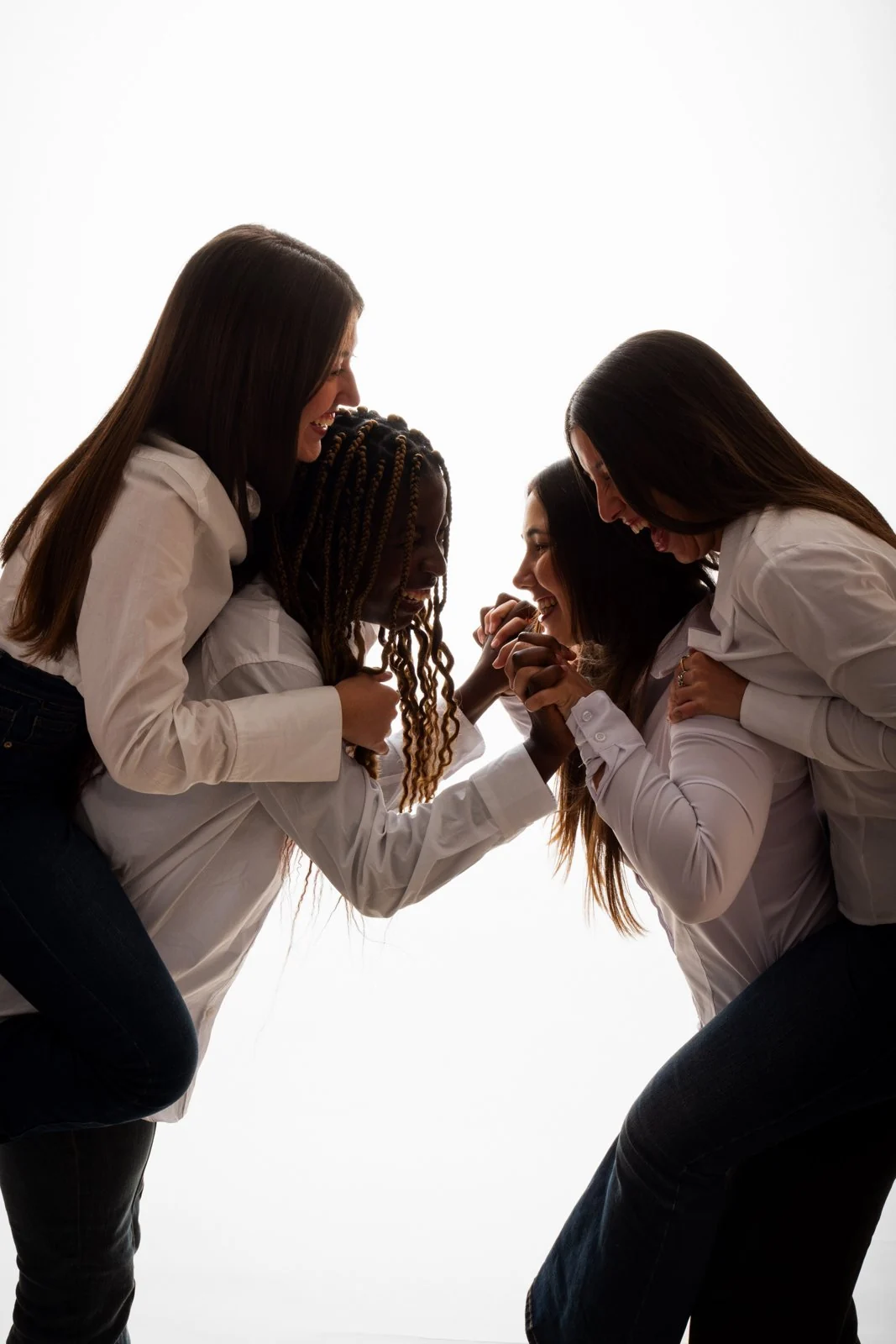 Cuatro amigas con camisa blanca ríen a contraluz en el estudio