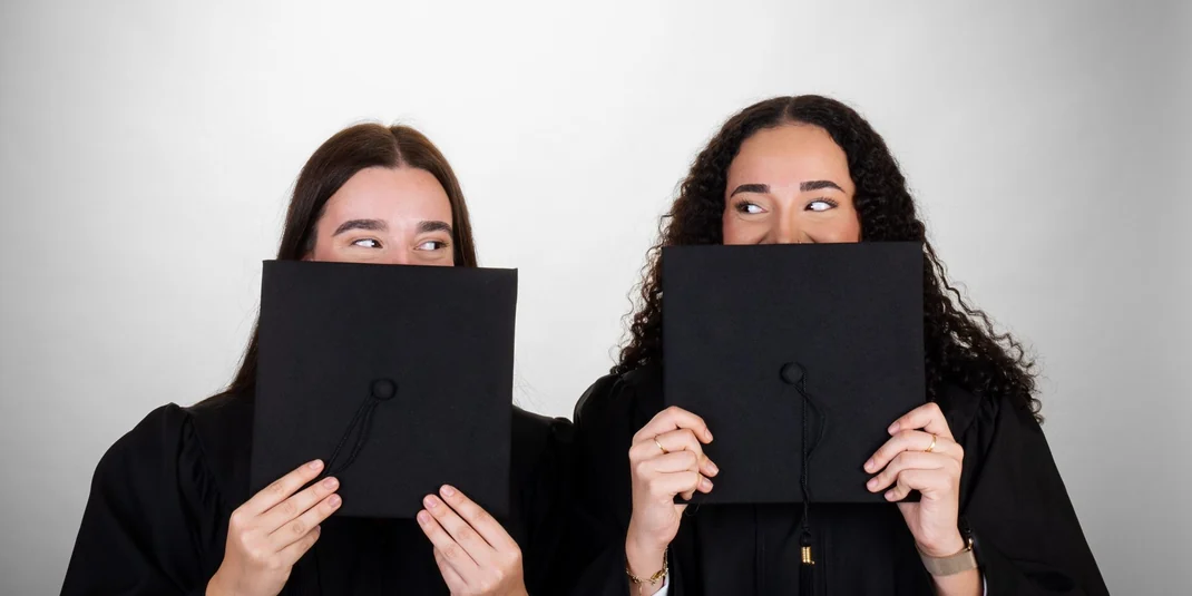 Dos graduadas escondidas tras el birrete