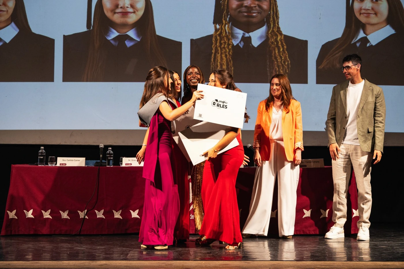 Graduadas reciben sobre el escenario el sobre de MagicOrles con sus fotos